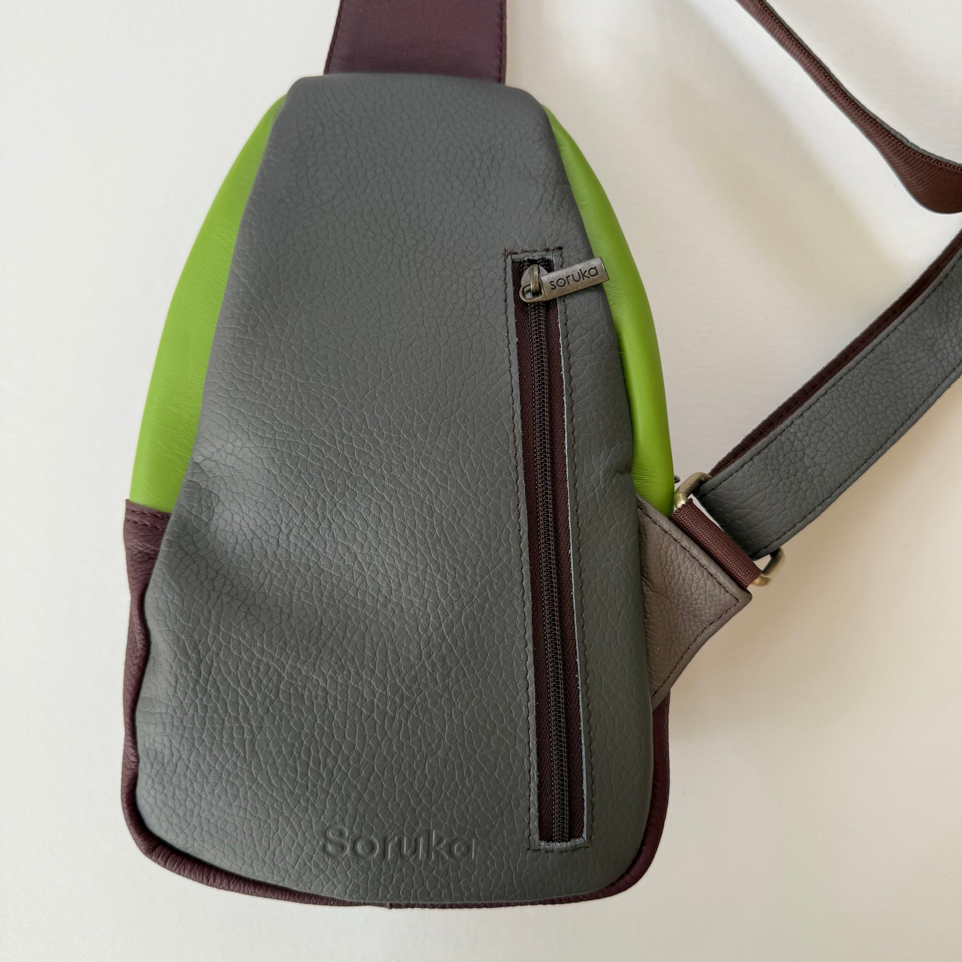 back view of grey sling bag with zippered pocket