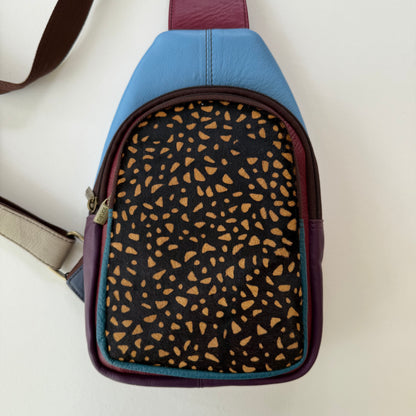 blue and purple sling bag with black and brown animal pattern front pocket