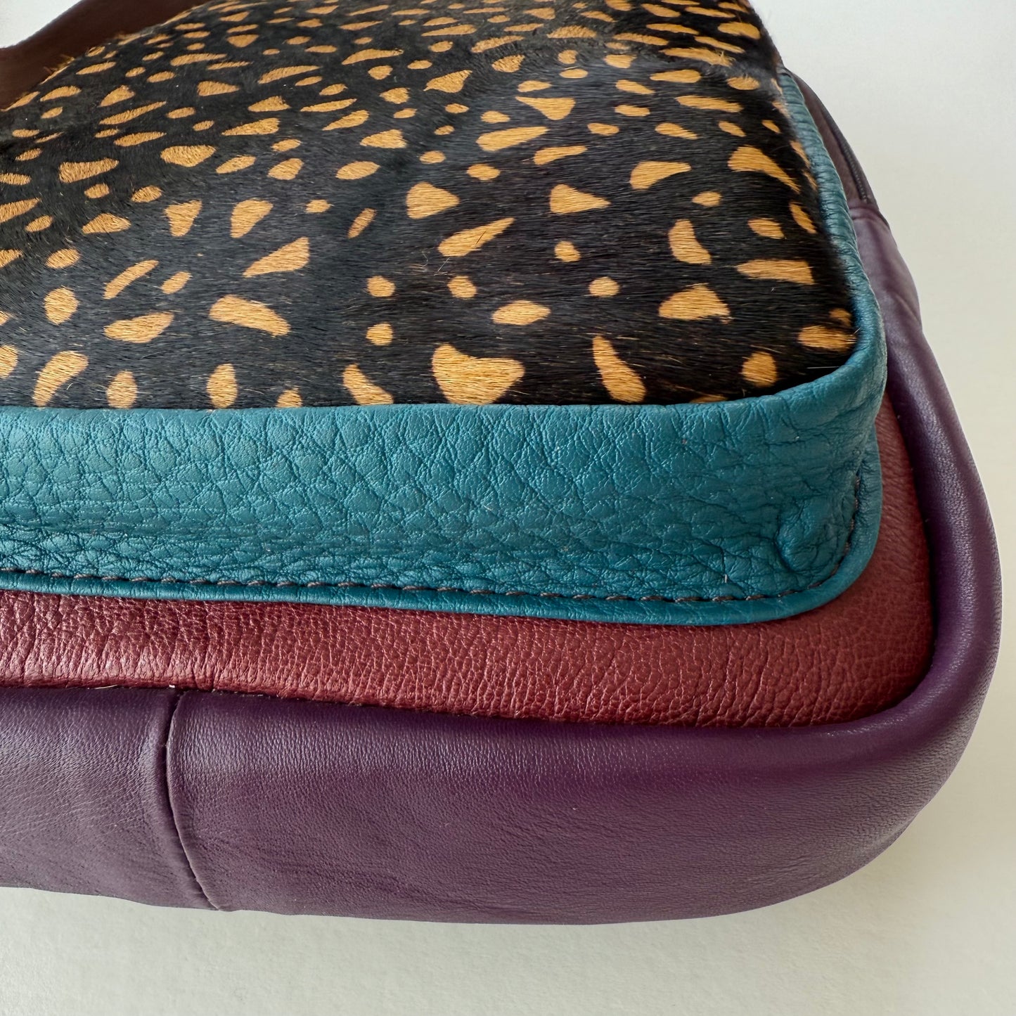 close-up of bottom corner of multi-colored sling bag