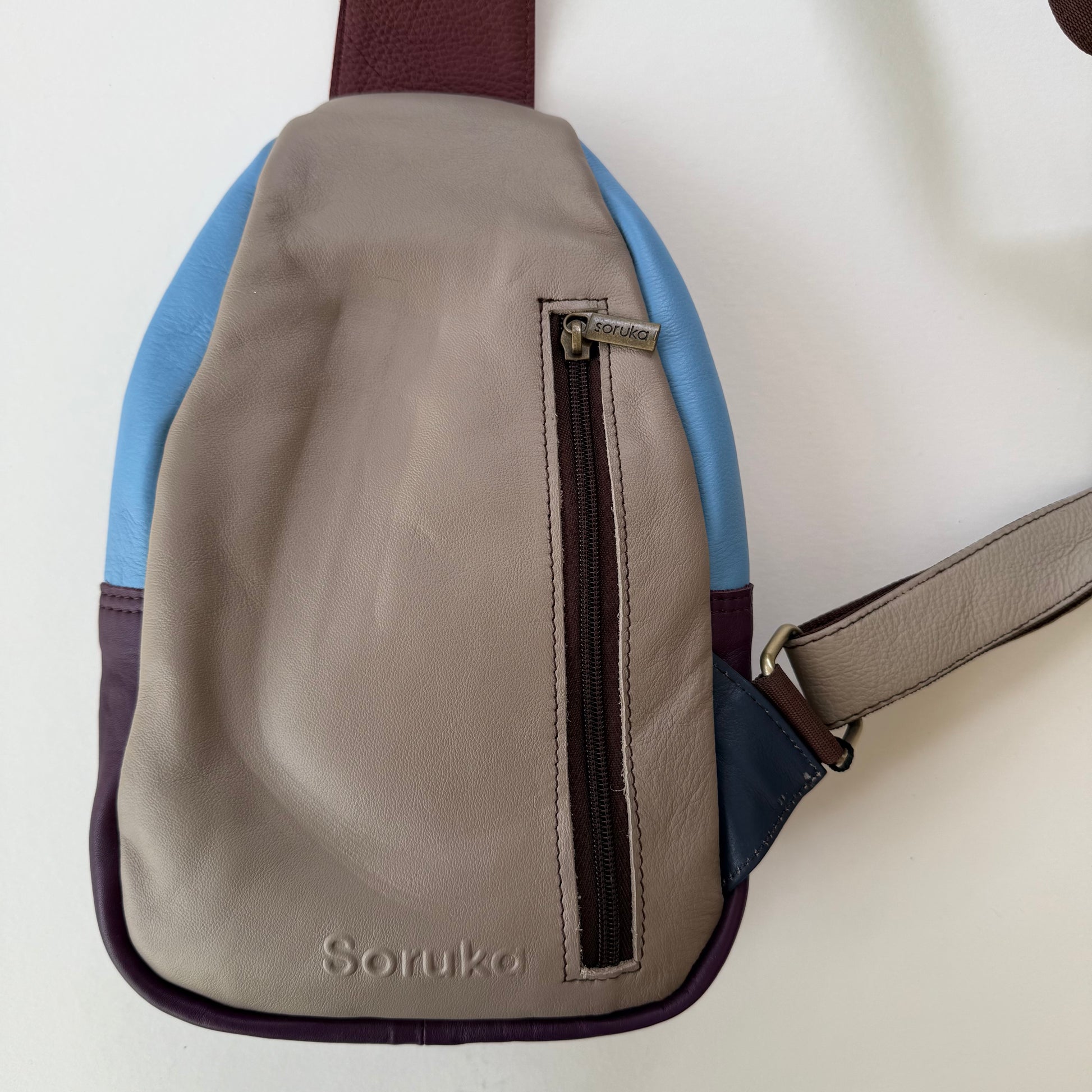 back view of grey sling bag with zippered pocket