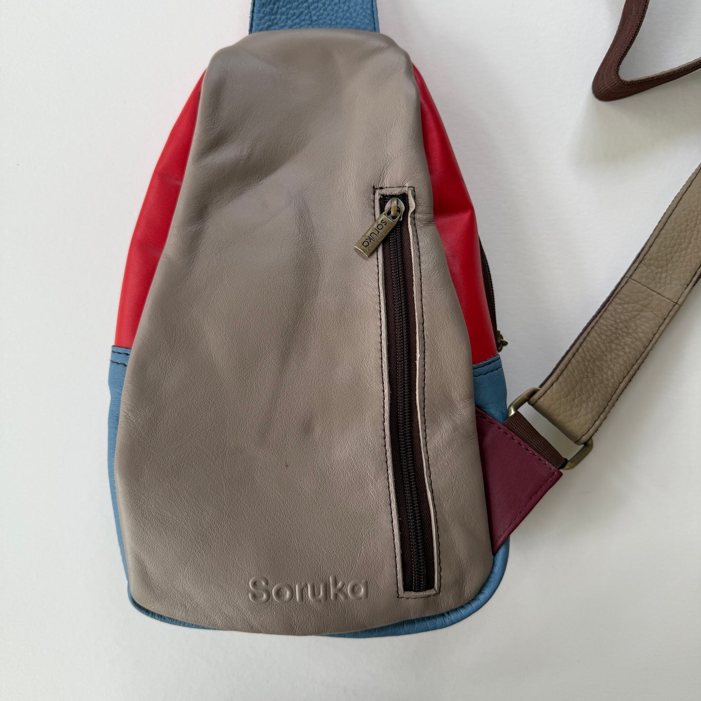back view of grey sling bag with zippered pocket