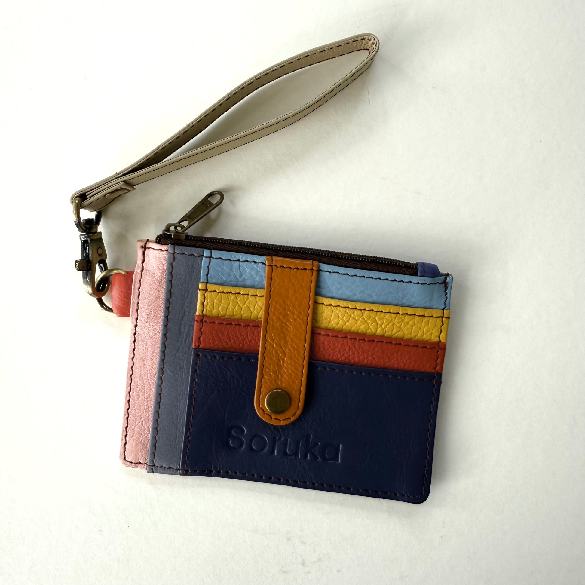 small wallet with colorful card slots, a orange tab, and taupe wristlet strap
