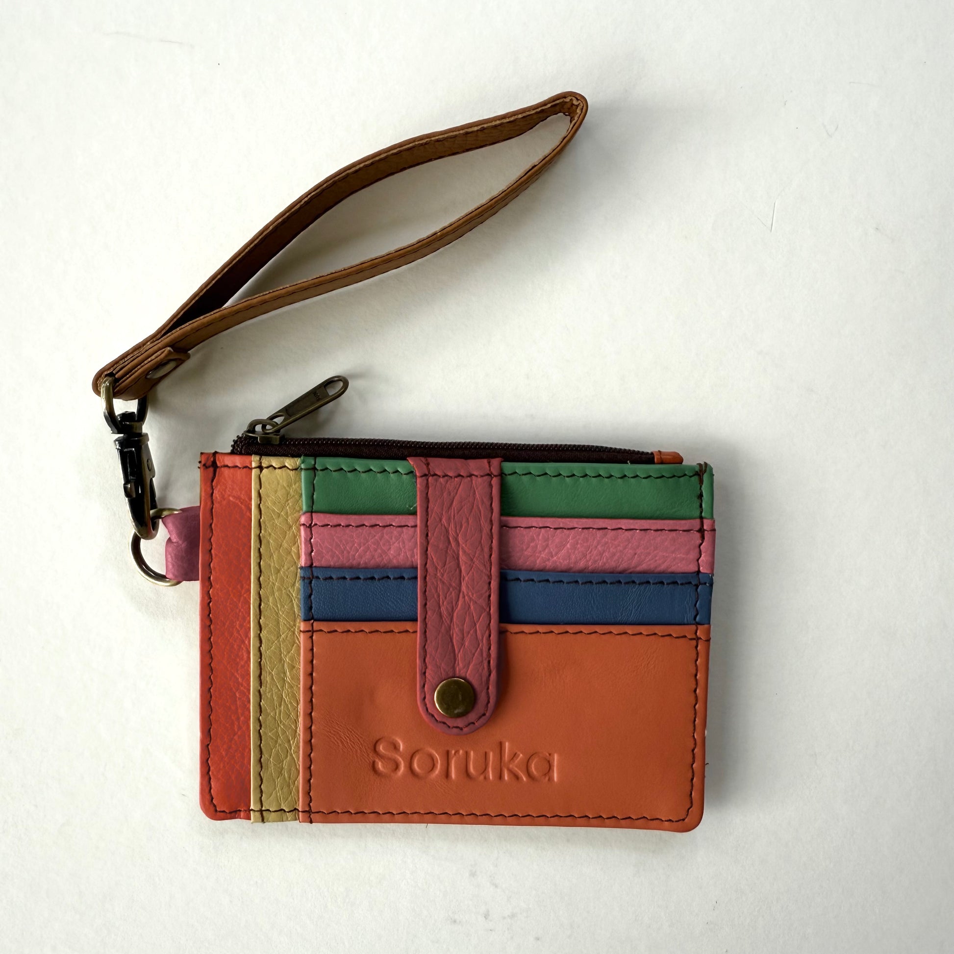 small wallet with colorful card slots, a pink tab, and brown wristlet strap
