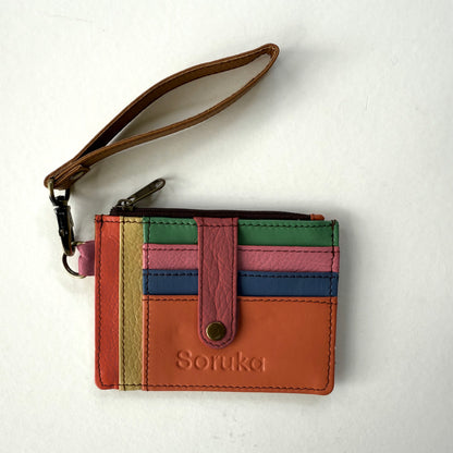 small wallet with colorful card slots, a pink tab, and brown wristlet strap
