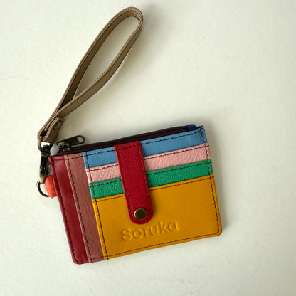small wallet with colorful card slots, a red tab, and taupe wristlet strap