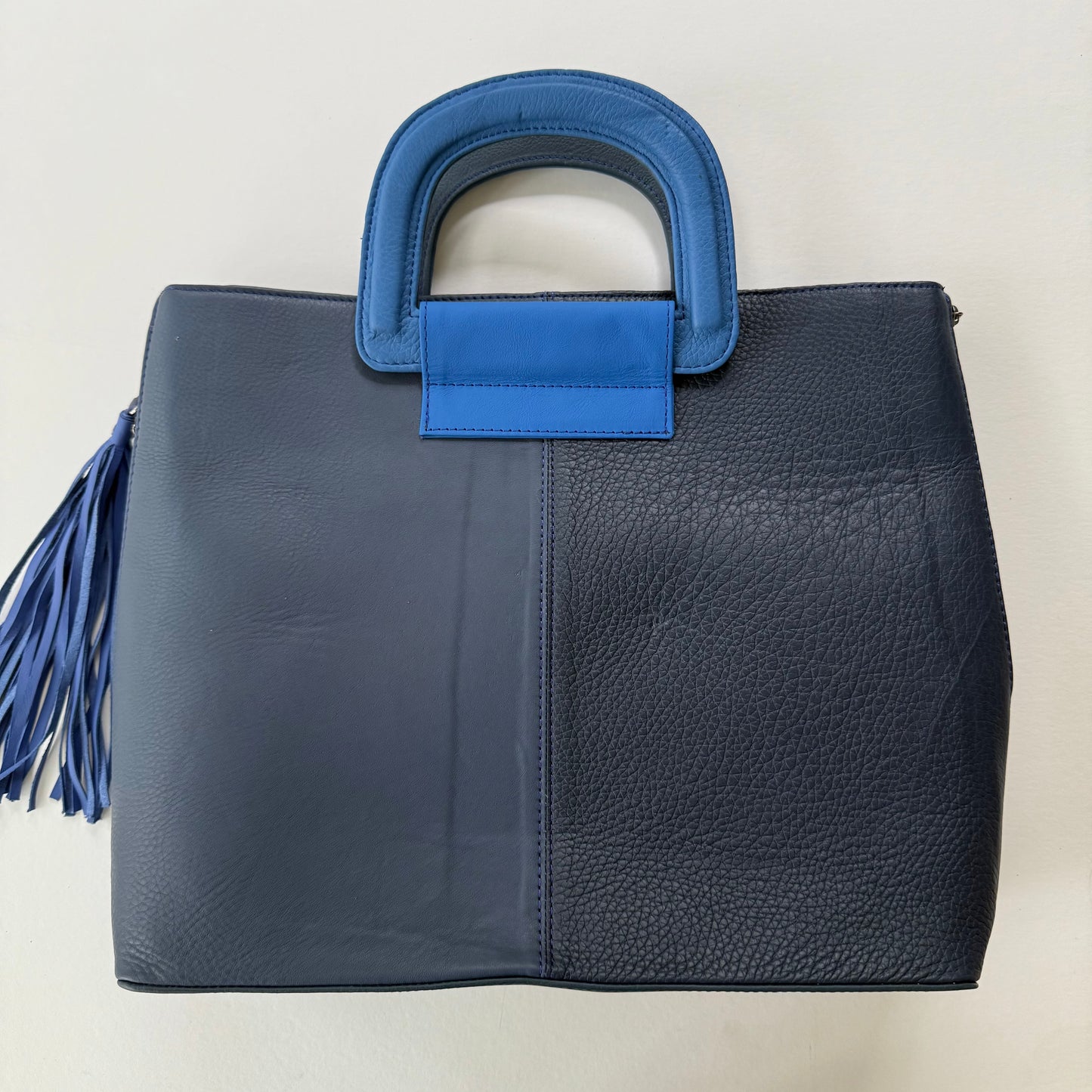 other side of blue leather tote bag in shades of dark blue with blue tassel