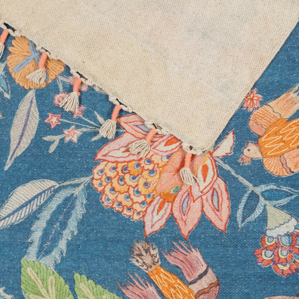 Close-up of a floral and bird patterned rug with fringe.