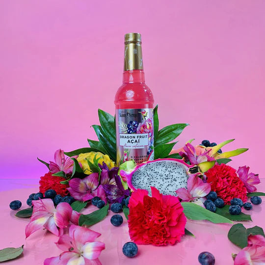 bottle of dragon fruit acai skinny syrup arranged with flowers and fruit.