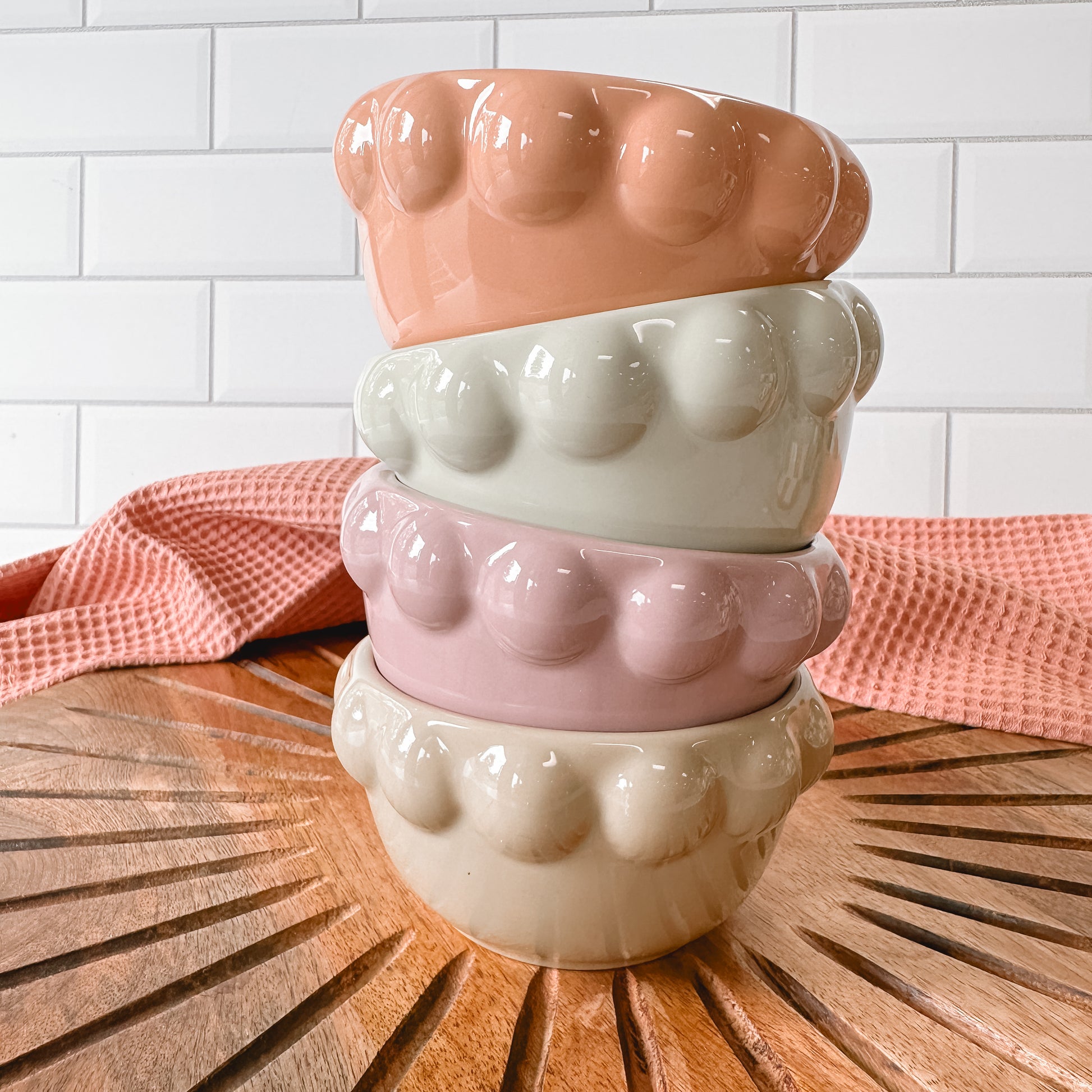 stack of 4 Stoneware Bowls with Bubble Rims set on a wooden surface with a white tile background