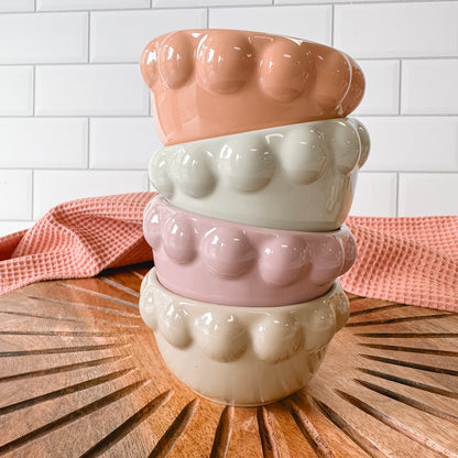 stack of 4 Stoneware Bowls with Bubble Rims set on a wooden surface with a white tile background