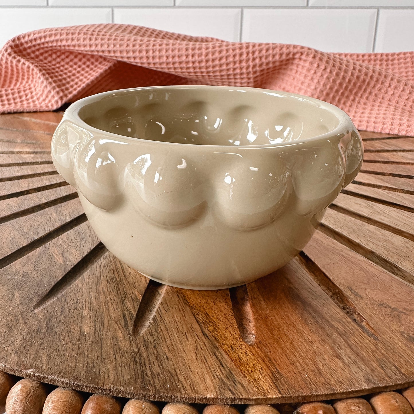 taupe ceramic little bowl with a raised dotted rim set on a wooden board