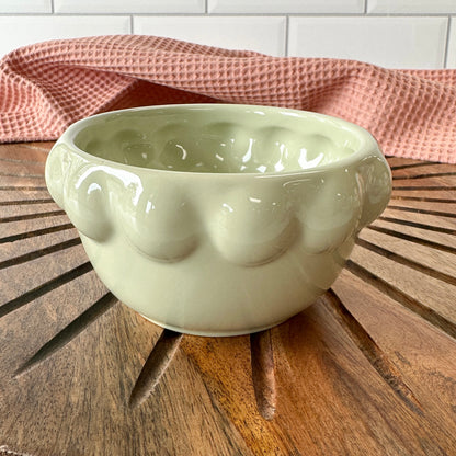 light green ceramic little bowl with a raised dotted rim set on a wooden board