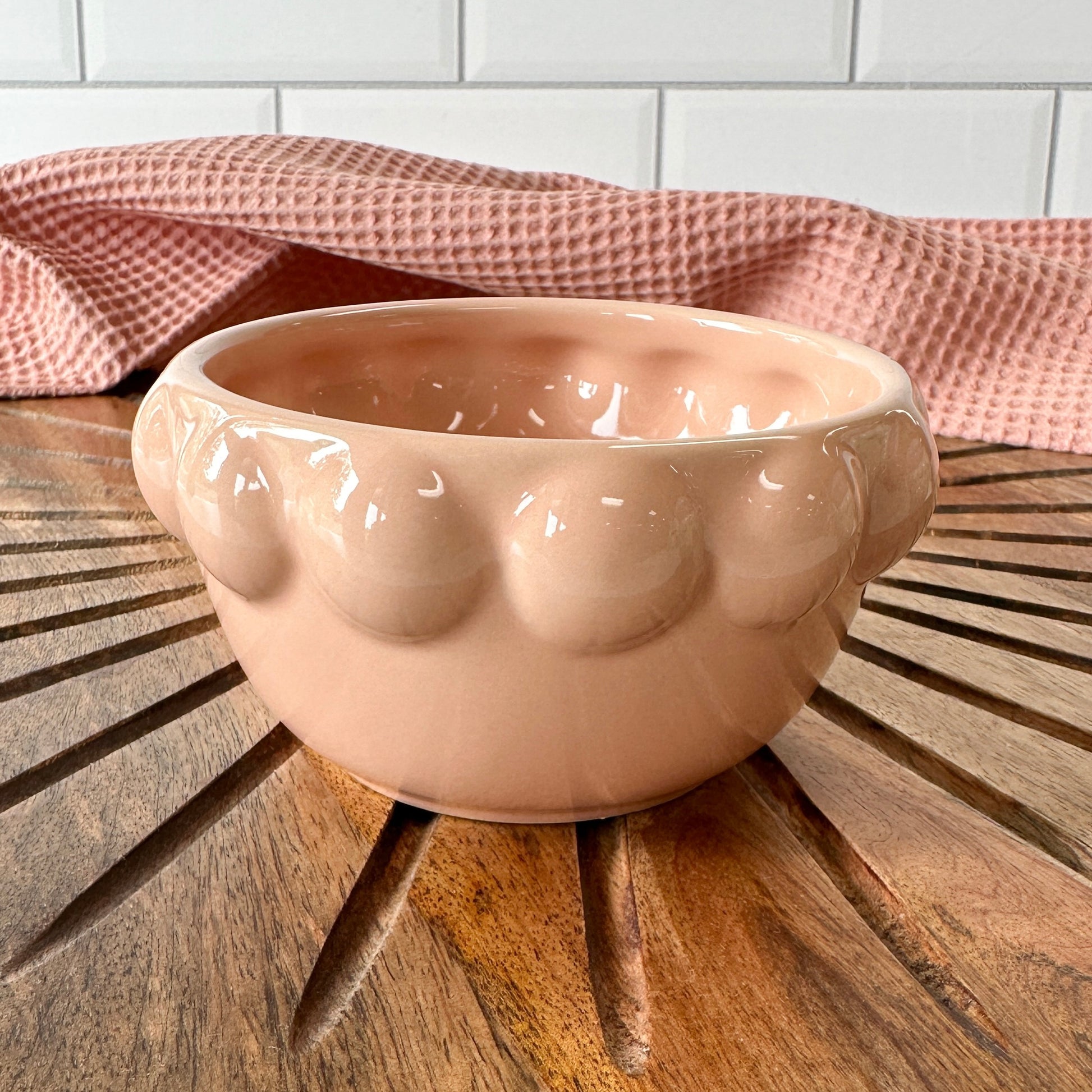 blush ceramic little bowl with a raised dotted rim set on a wooden board