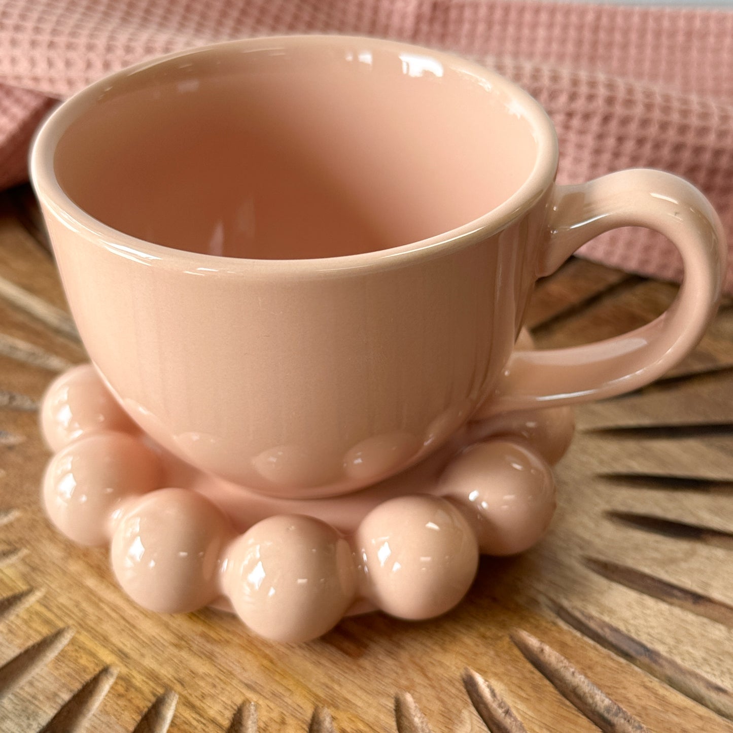 blush Stoneware Mug with Bubble Saucer set on a wooden board