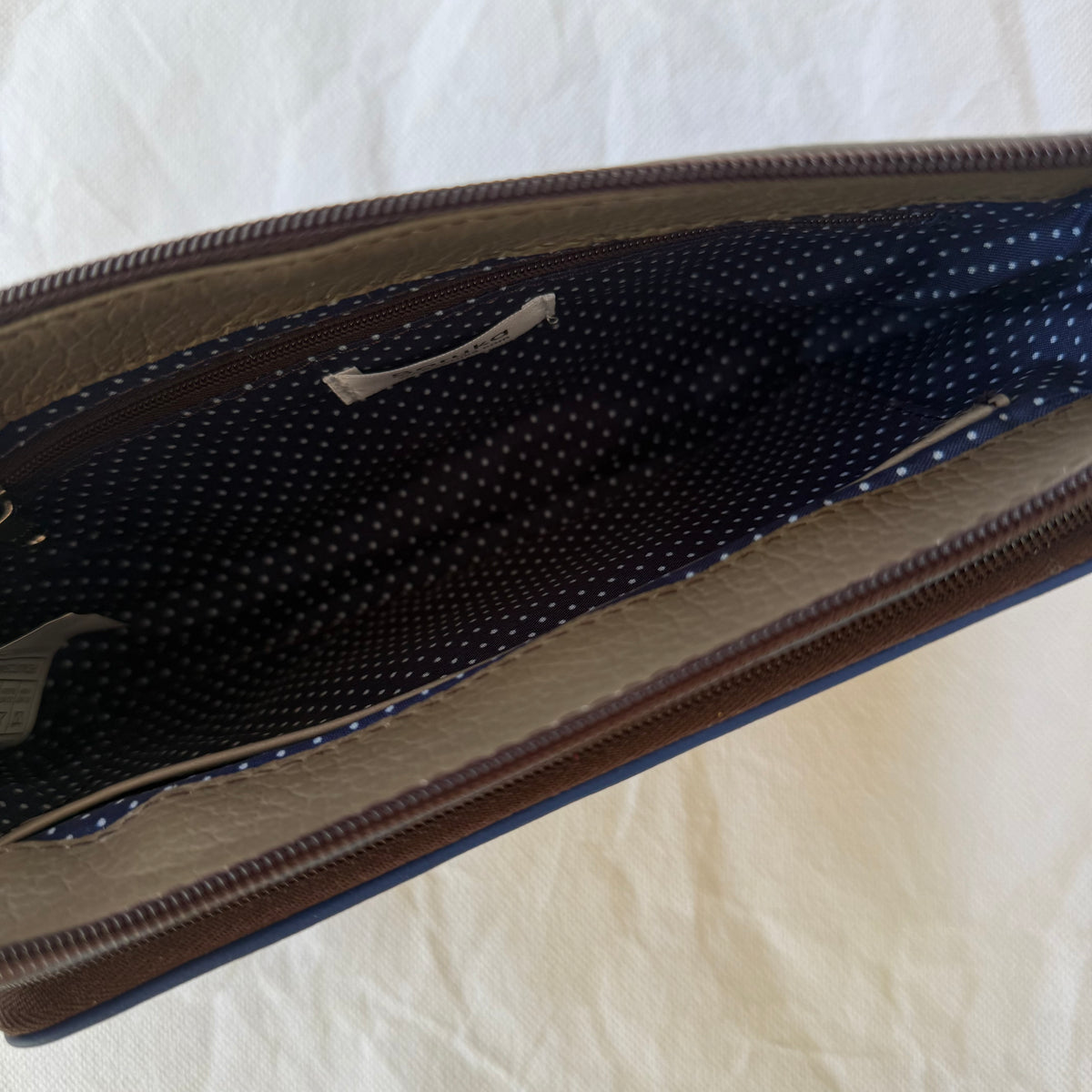 interior view of small crossbody showing blue dot lining and zippered pocket