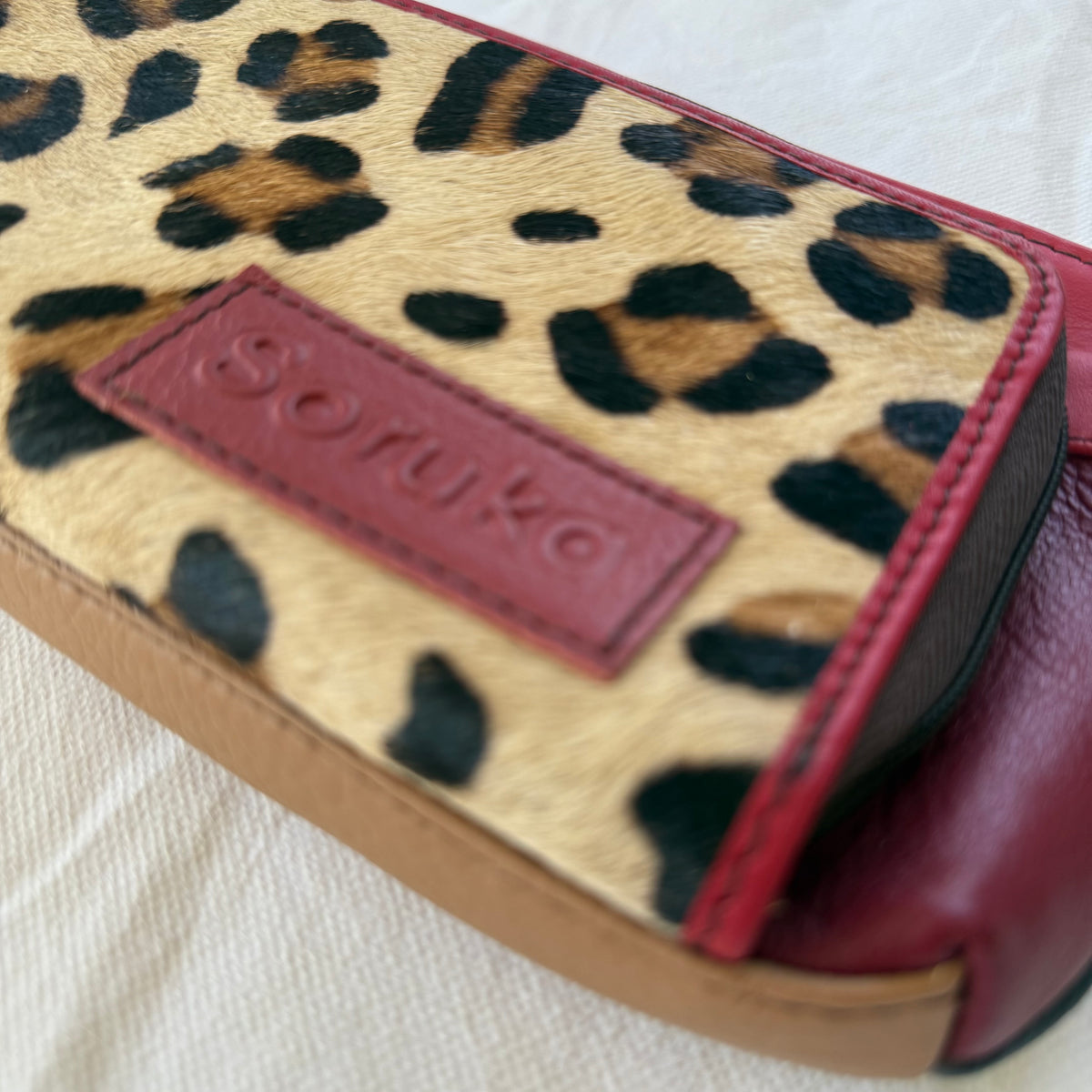 close-up of small red crossbody purse with leopard print front pocket