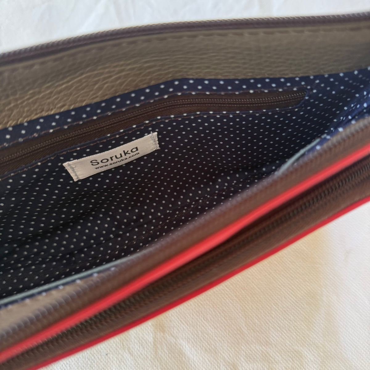 interior of view of small crossbody with blue polka dot lining and zip pocket