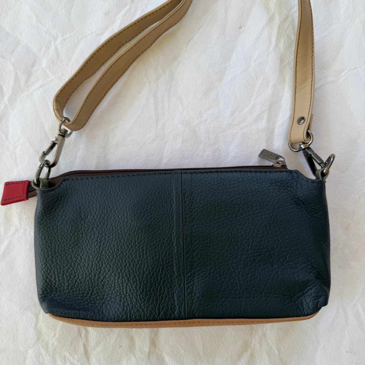 back view of small crossbody with blue  leather backing