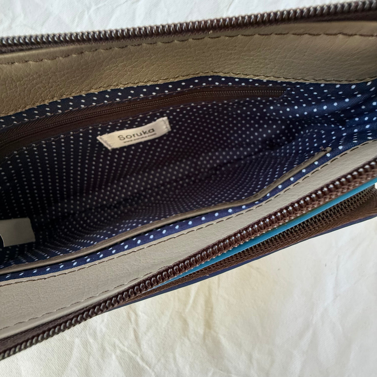 interior view of small crossbody purse with blue lining and zippered pocket
