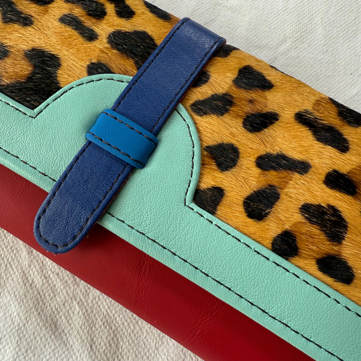 close-up of wallet with leopard flap, red body, and light and bright blue trim