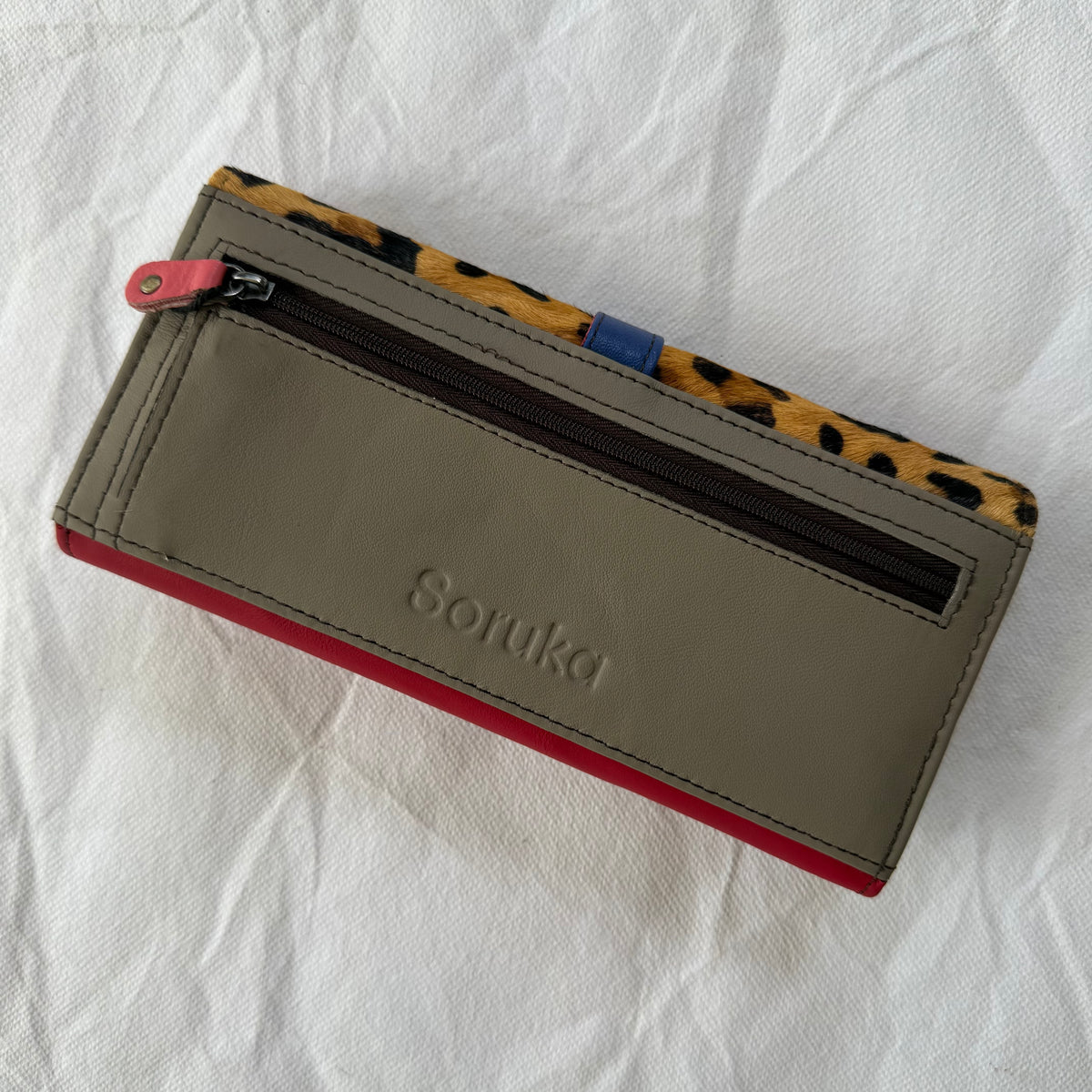 back view of wallet with taupe backing and zippered pocket