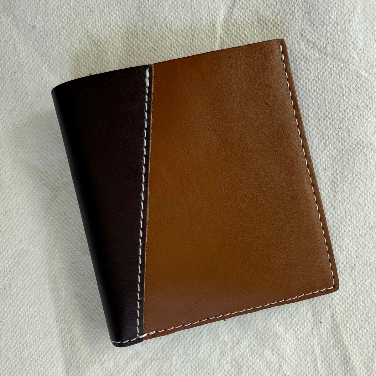 other side of wallet with light and brown leathers and white stitching