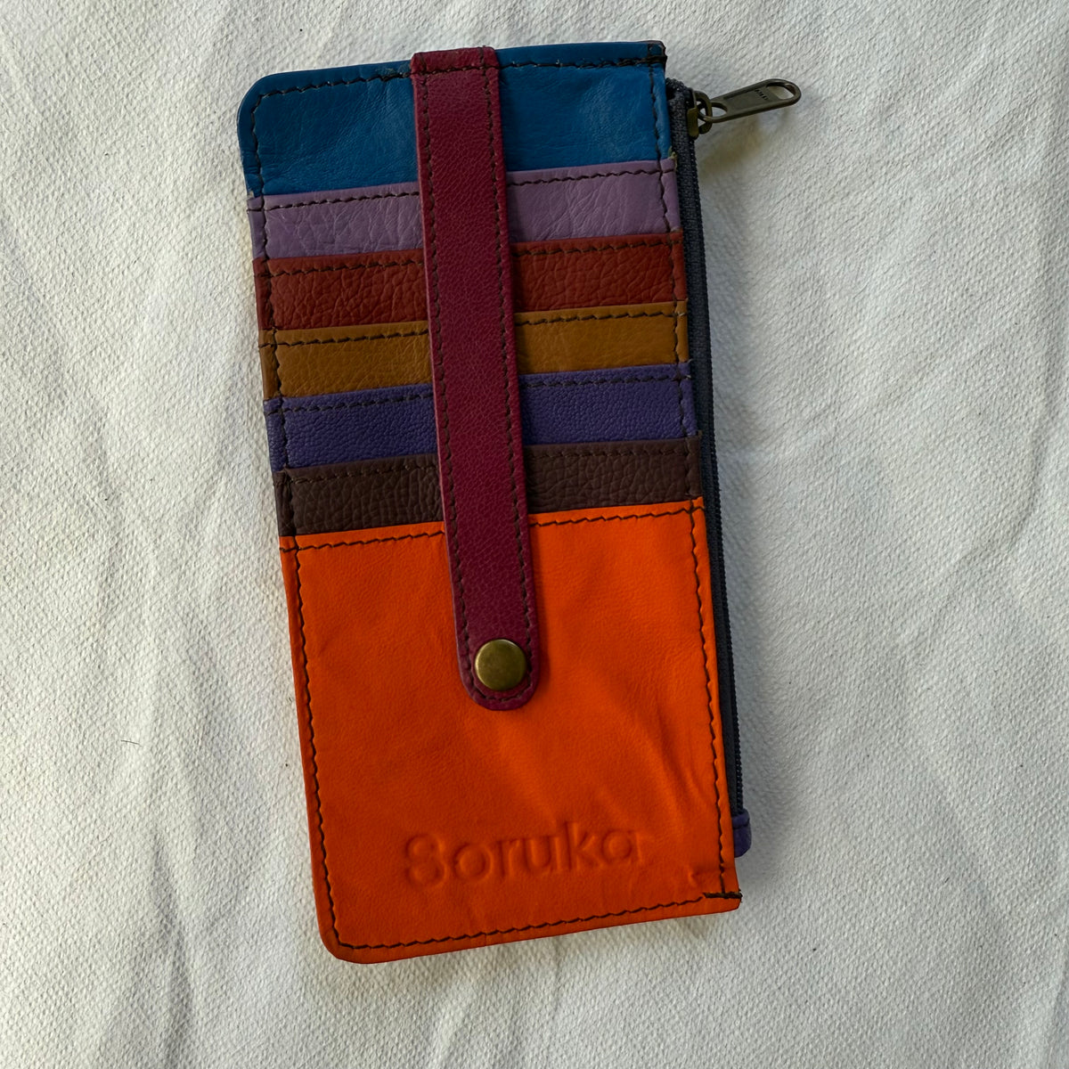 flat wallet with colorful card slots in orange, blues, and reds and a zip pocket along the side