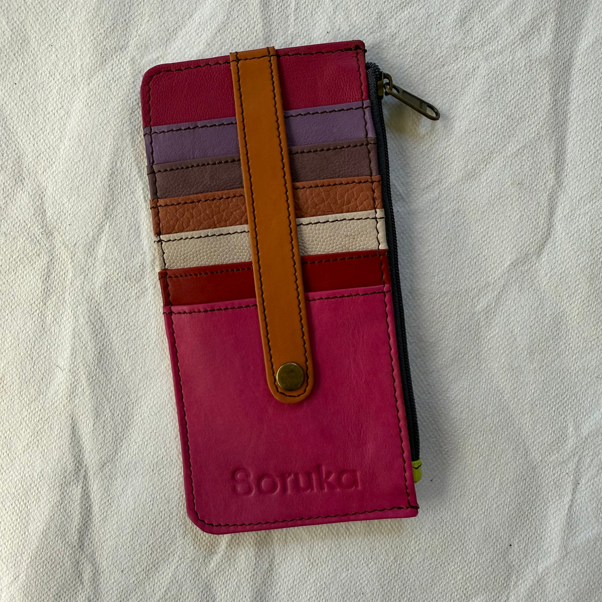 flat wallet with colorful card slots in pink and brown hues and a zip pocket along the side
