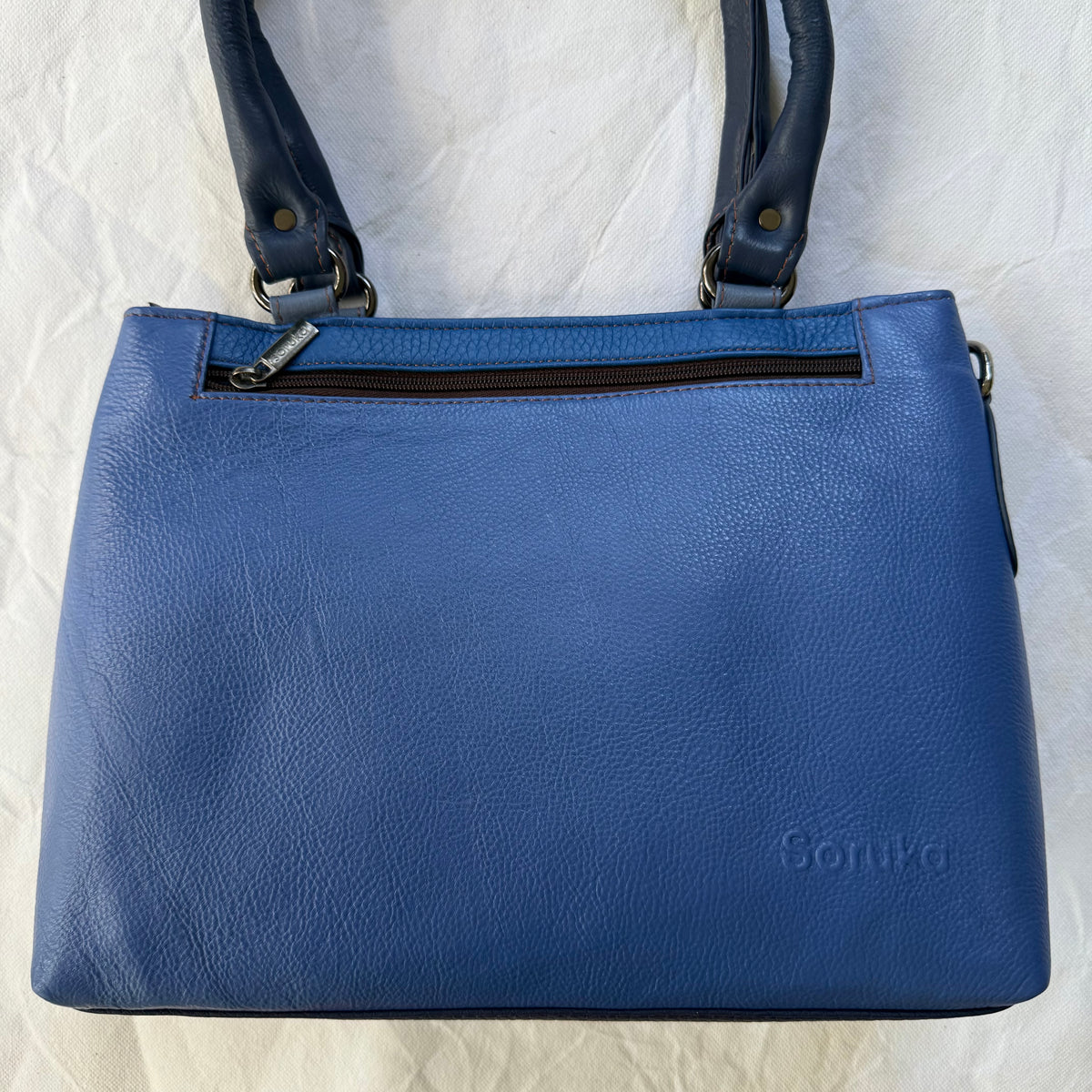blue leather handbag with top zipper pocket and 2 dark blue shoulder straps