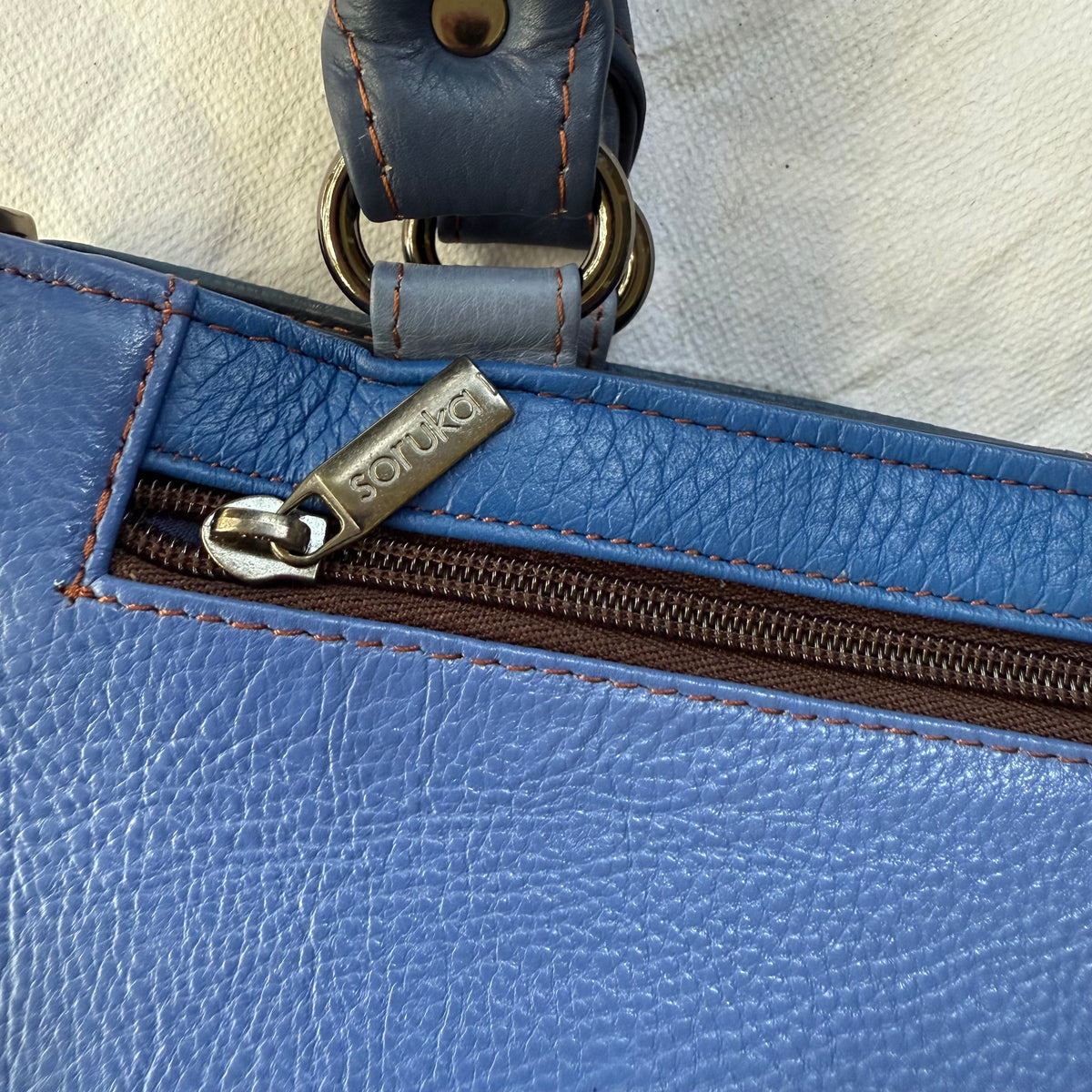 close-up of blue handbag with zippered pocket