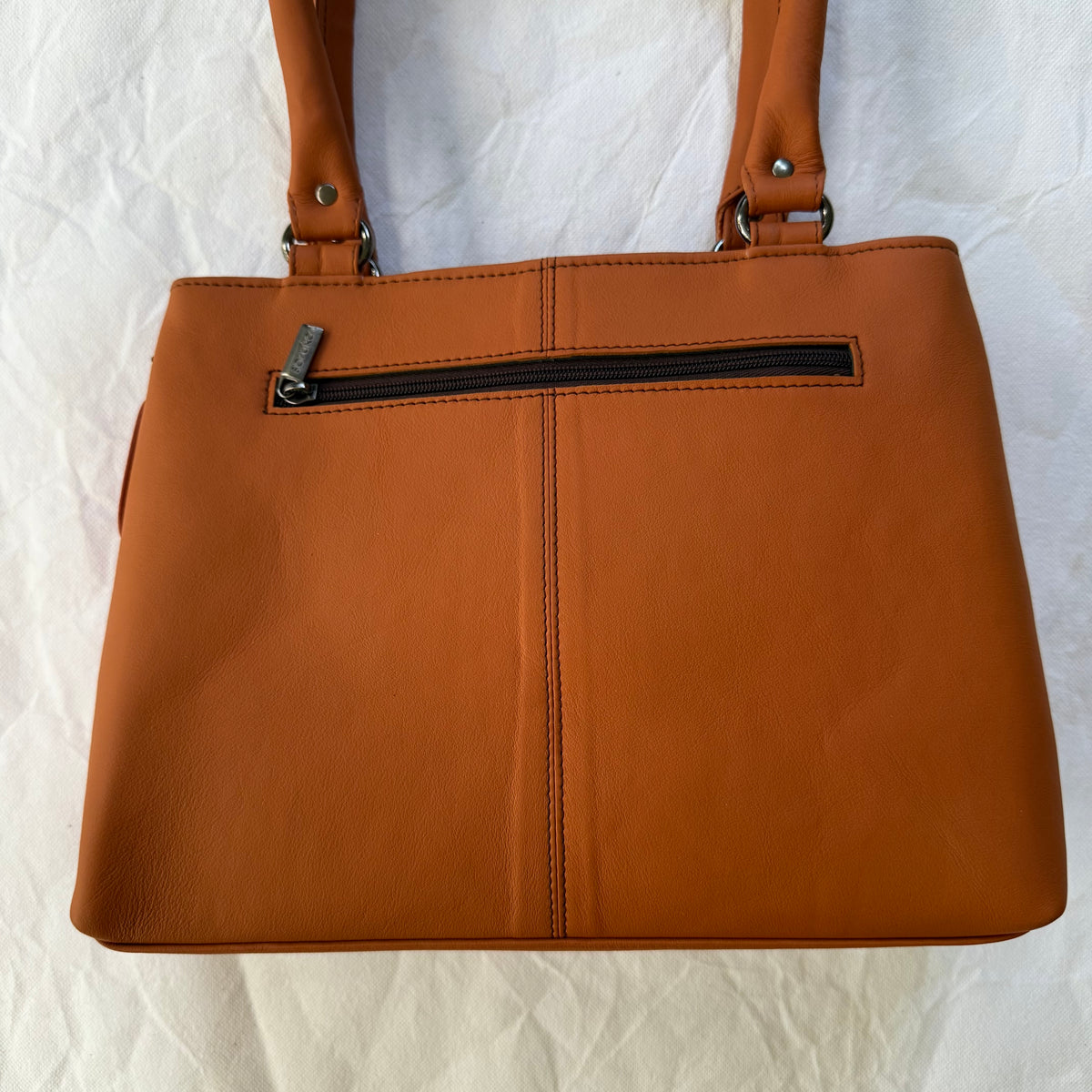 warm orange leather handbag with zipper pocket across the top