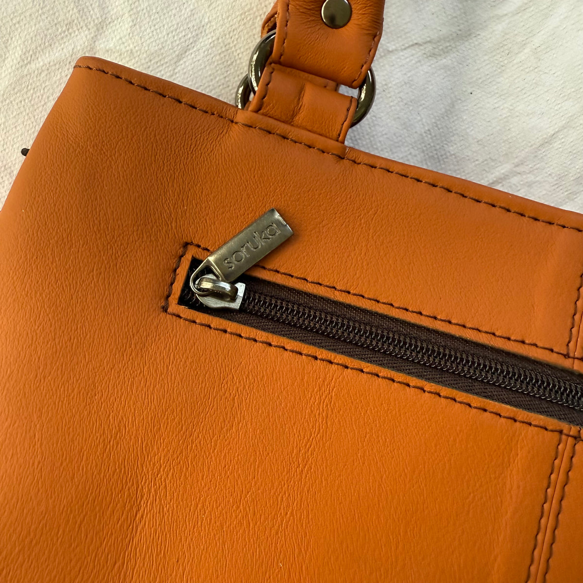 close-up of orange leather handbag with zipper pocket