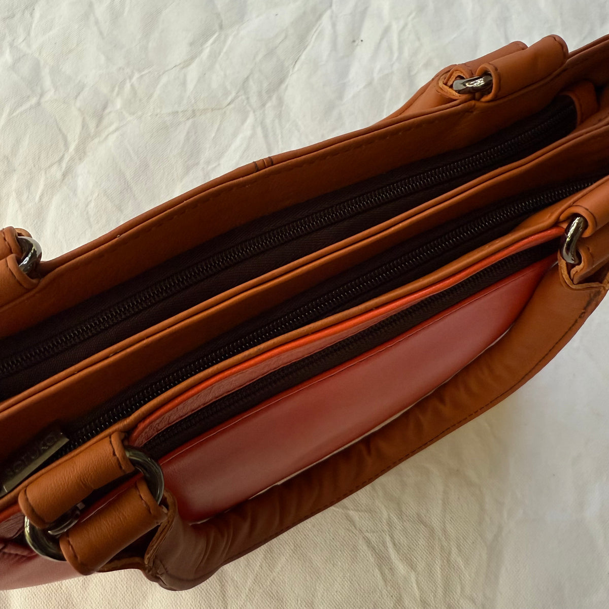 top view of orange leather handbag with 2 zipped compartments