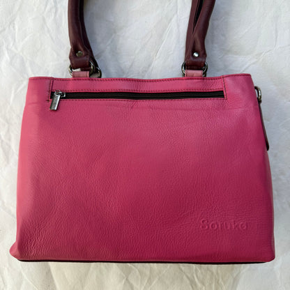 pink leather handbag with top zipper pocket and 2 maroon shoulder straps