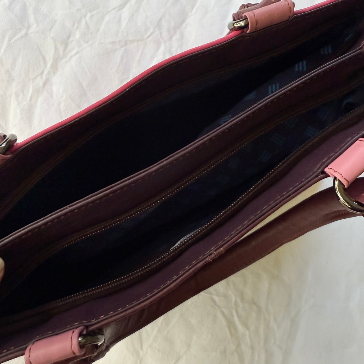 top view of pink handbag with 2 unzipped compartments showing blue interior
