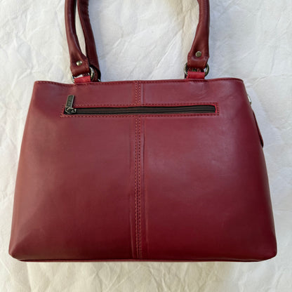 A deep red leather handbag with double shoulder straps and a front zippered pocket