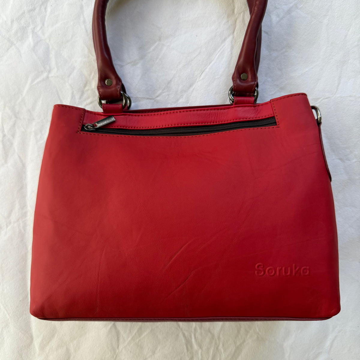 other side of handbag with bright red leather and zippered pocket