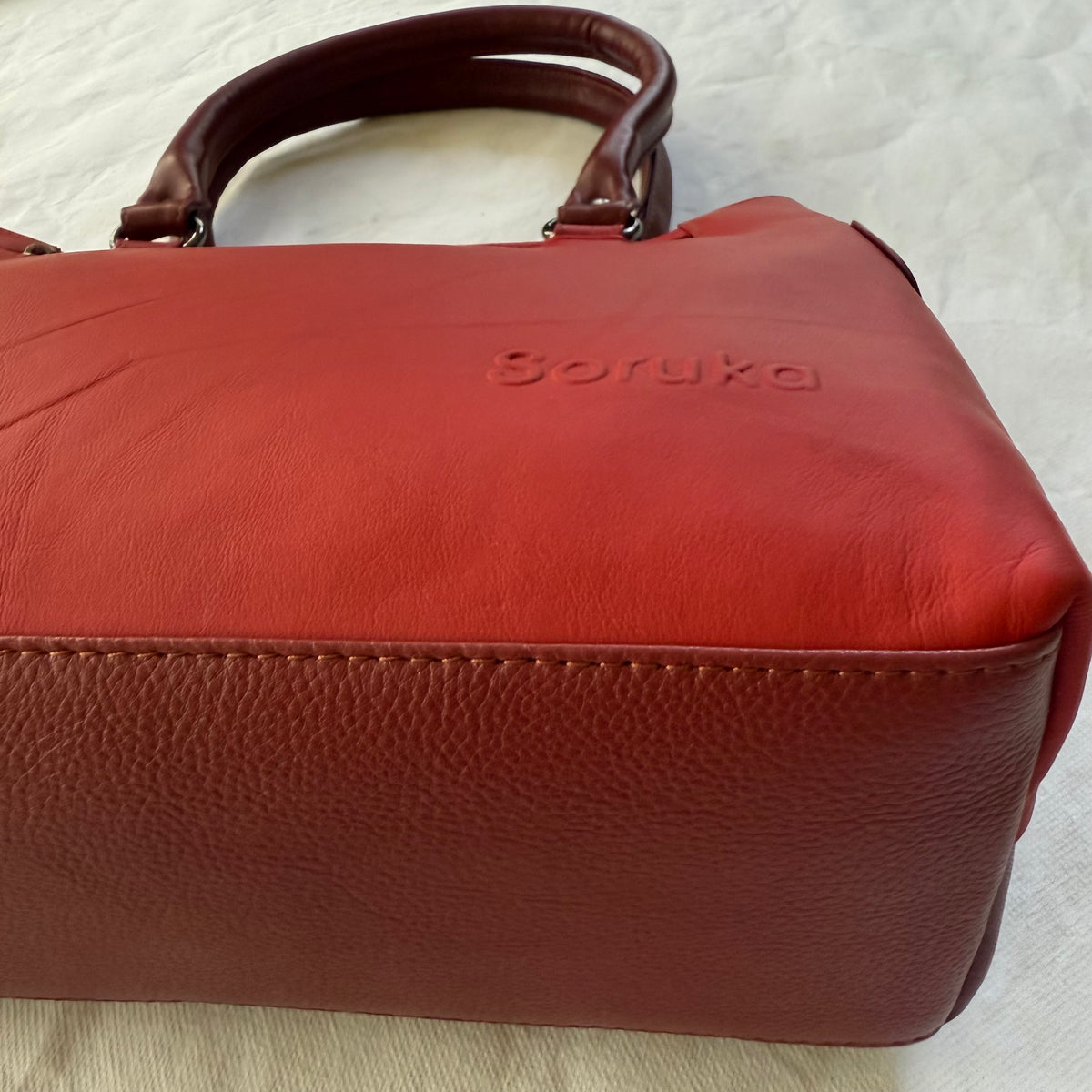 bottom view of red leather handbag with dark red bottom