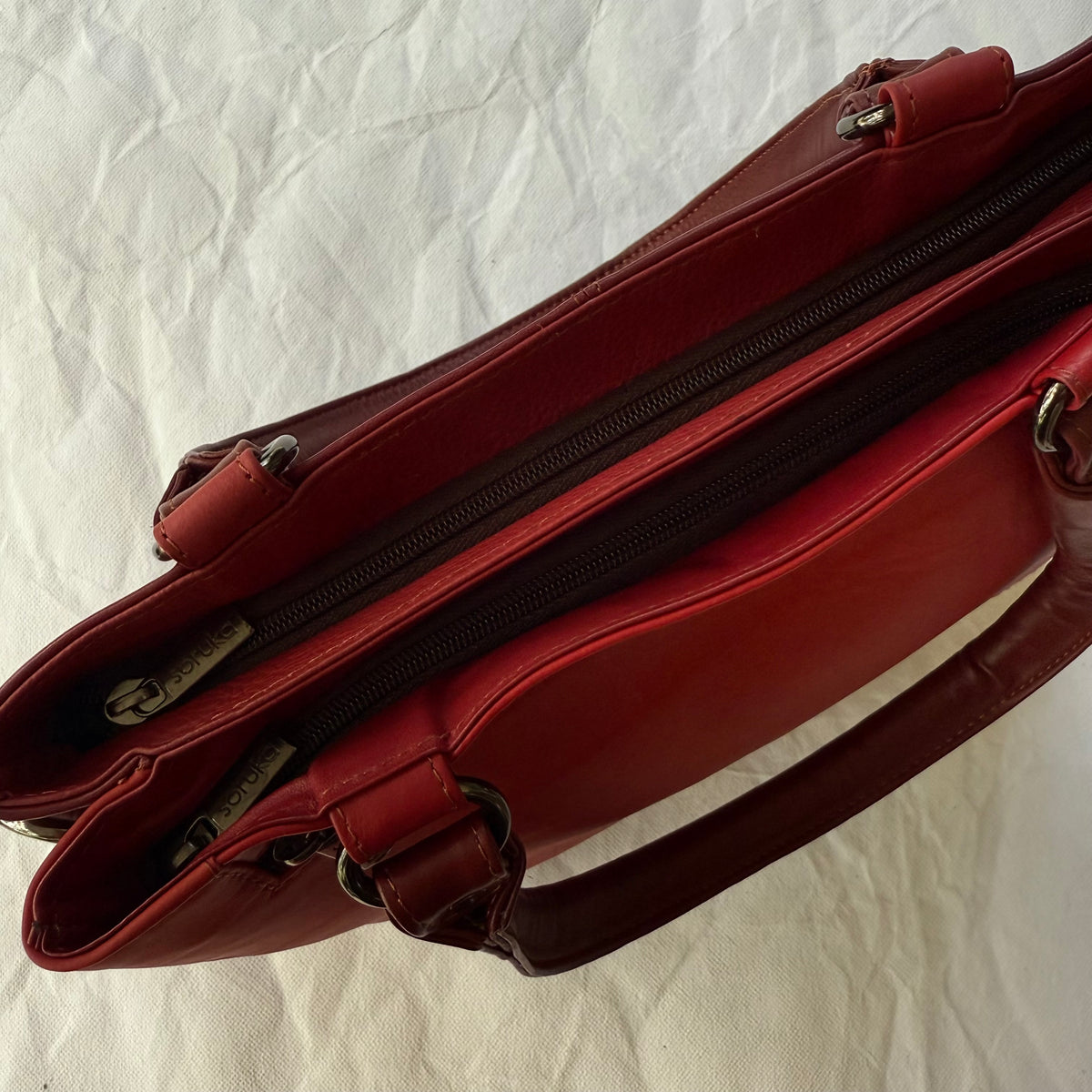 top view of red handbag showing 2 zipped compartments