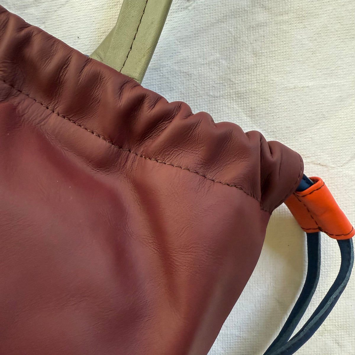 close-up of top rim of cinched burgundy handbag
