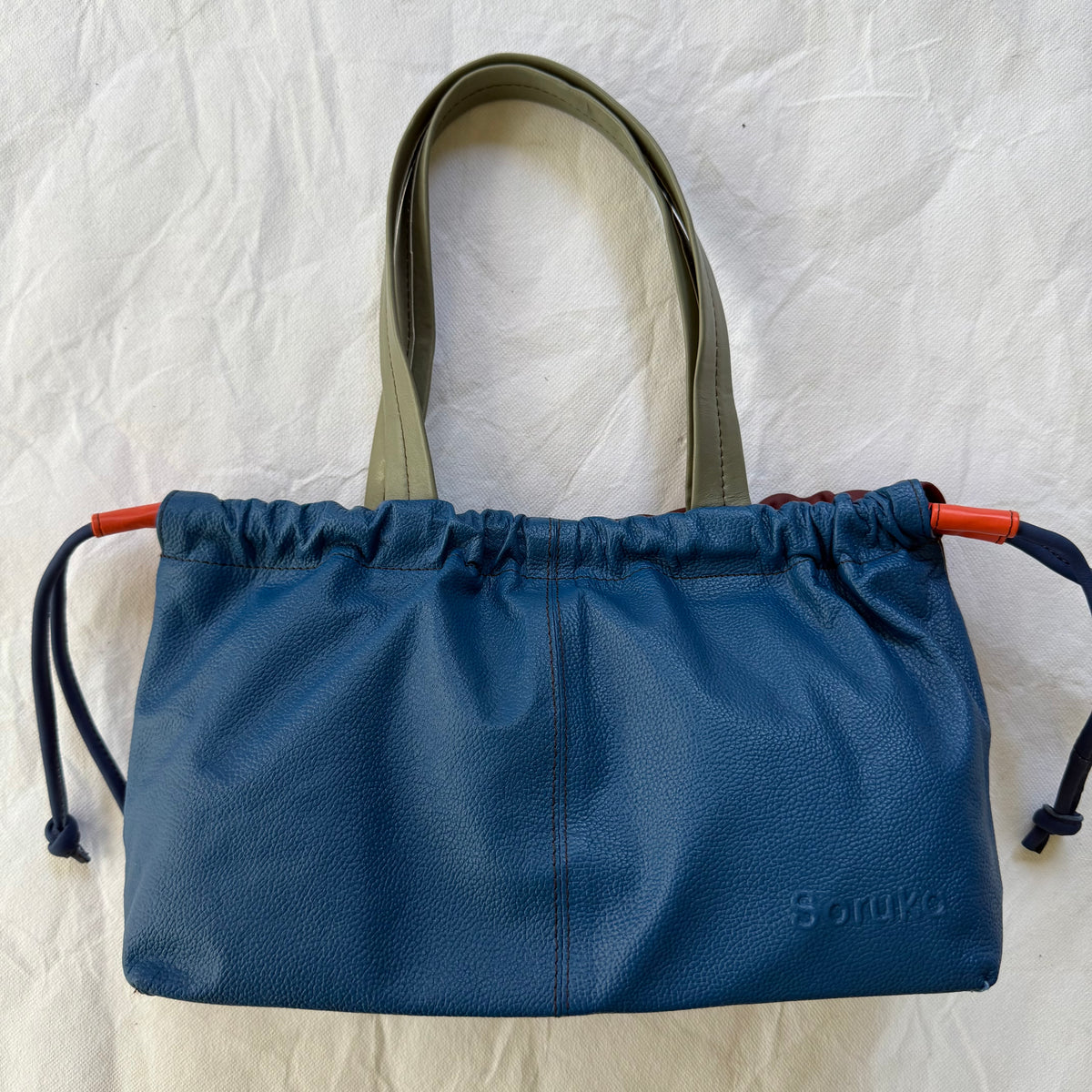 other side of handbag with blue leather and grey handles