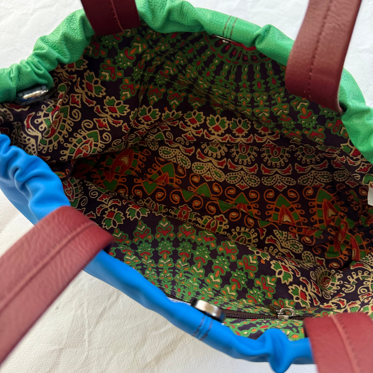 interior view of handbag showing patterned lining, zipper pocket, and magnetic snap closure