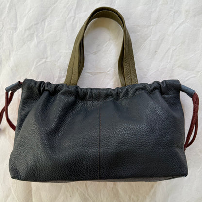navy handbag cinched slightly across the top with taupe-green handles