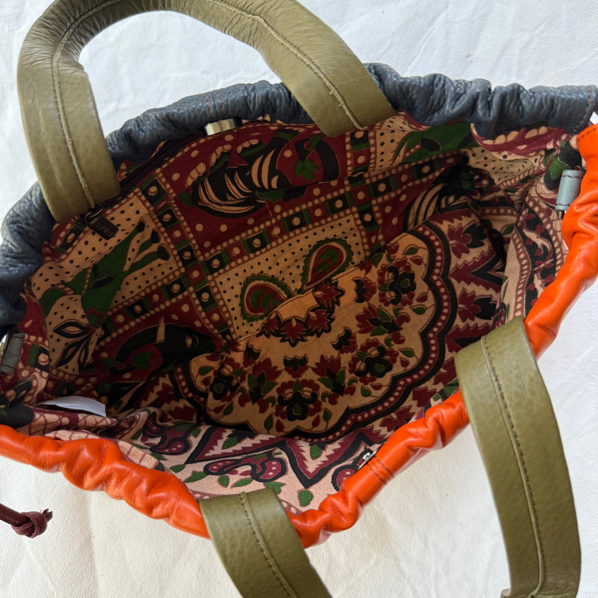 interior view of handbag showing patterned lining, zipper pocket, and magnet snap closure