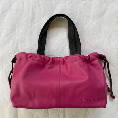 bright pink handbag with cinch design and grey handles