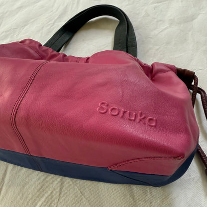 close-up of bottom of pink and blue handbag