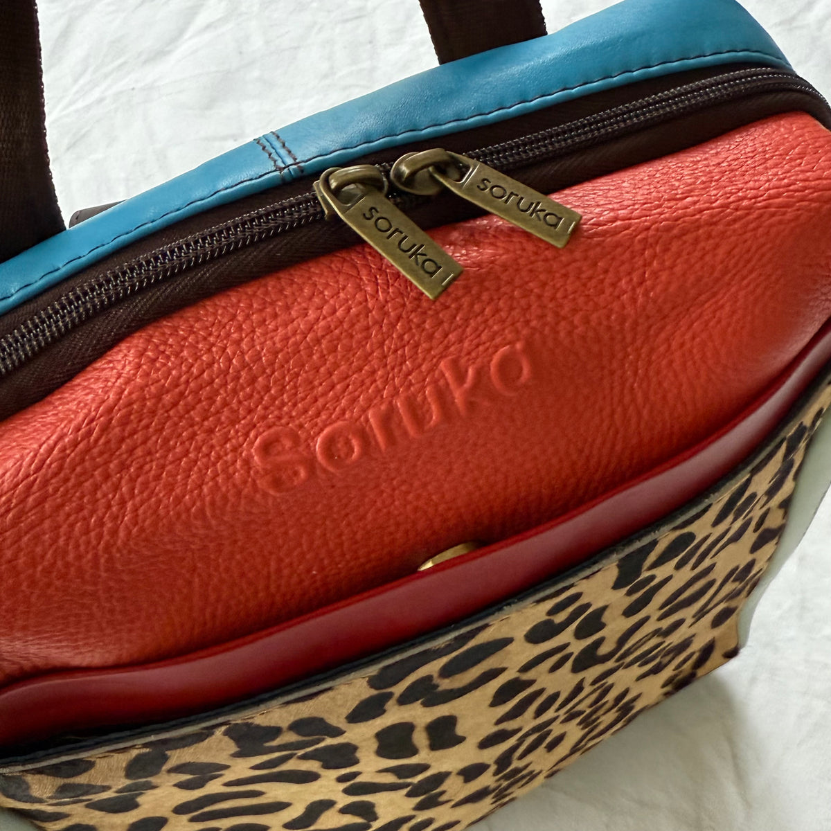 top view of backpack with coral and red top sections and animal print front panel