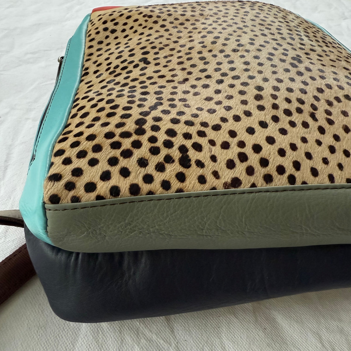 A close-up of bottom view of a backpack showing its color-blocked design. 