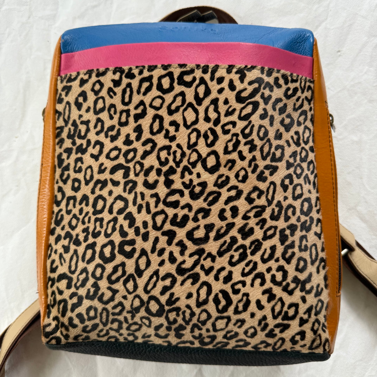 backpack with cheetah print front panel, orange side sections, and pink and blue top sections