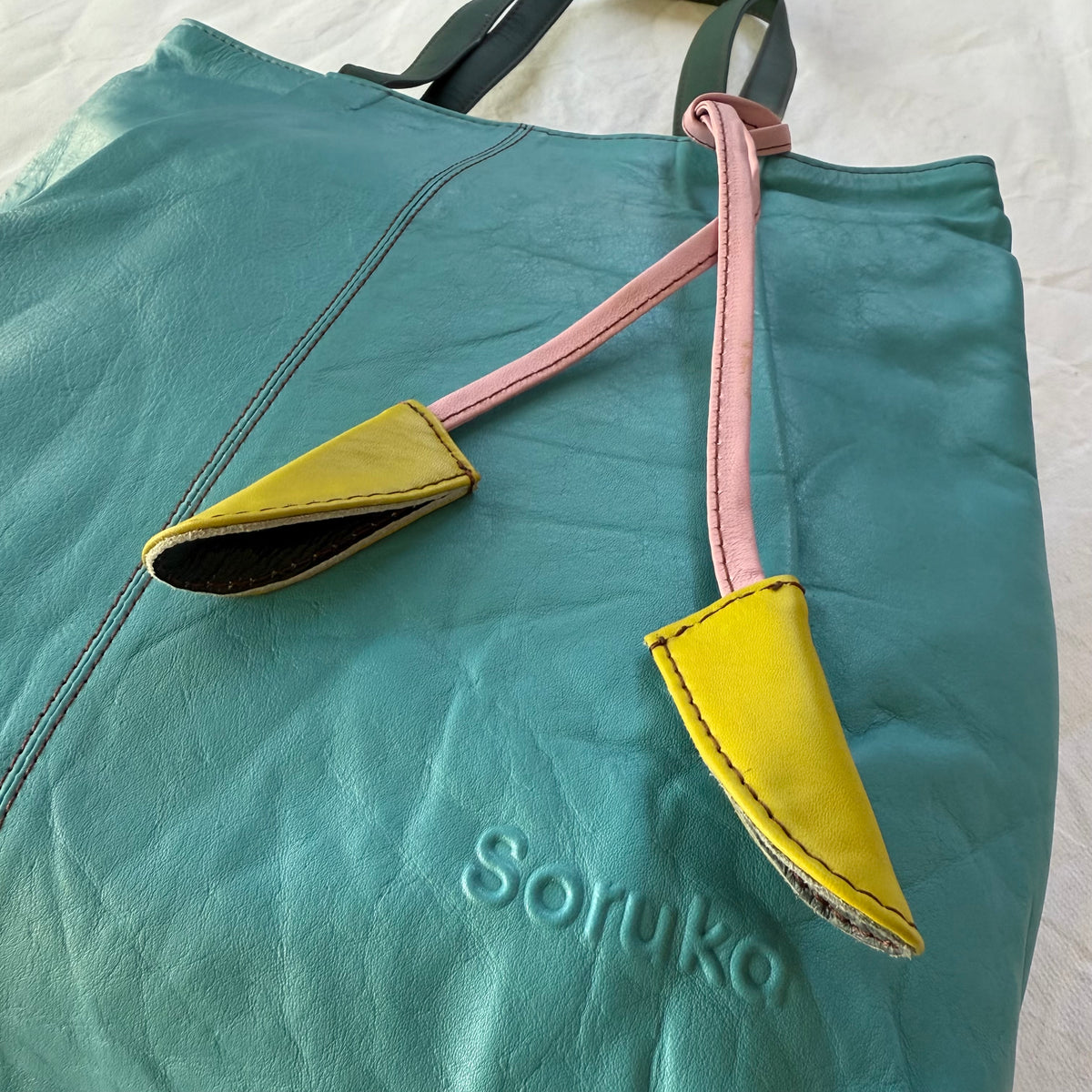 close-up of turquoise leather tote with tassels
